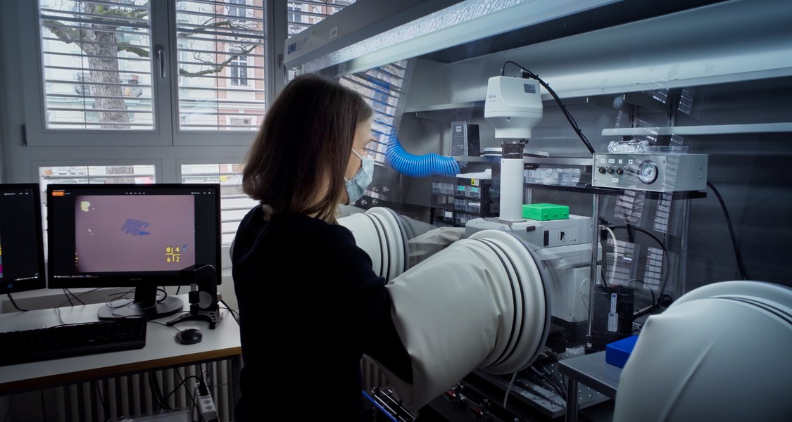 Foto of Nadine Leisgang standing in front of a glovebox with her arms inside the gloves