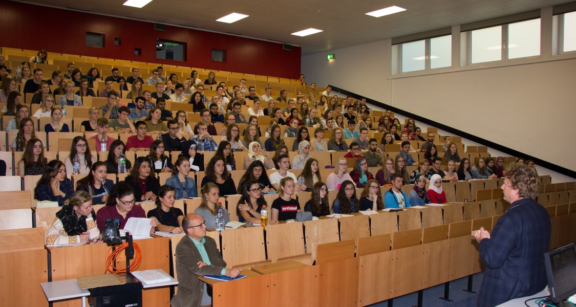 1. Semester Studierende im großen Hörsaal des Instituts für Pharmazeutische Chemie mit dem (stehend) Dekan des Fachbereichs Pharmazie, Prof. Dr. Michael Keusgen und (1. Reihe) Prof. Dr. Thorsten Steinmetzer (Foto: Regina Gerlach-Riehl)