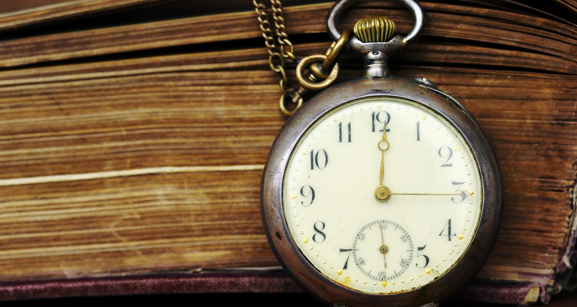 Eine alte Taschenuhr lehnt an einem Buch