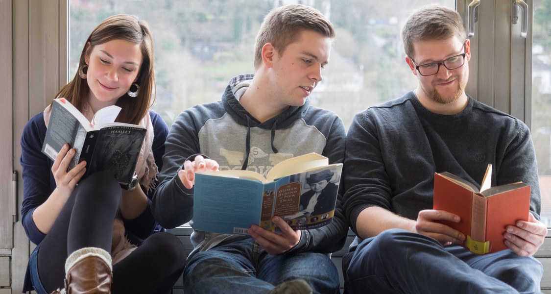 Studierende lesen Bücher vor Fenster