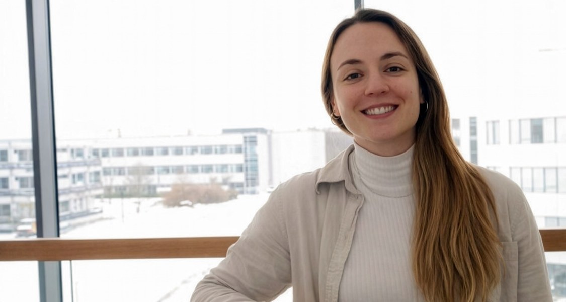 Dr. Aina Lluch lächelt in einem hellen Innenraum vor großen Fenstern