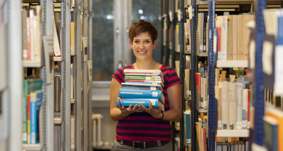 Studentin mit Büchern in Bibliothek