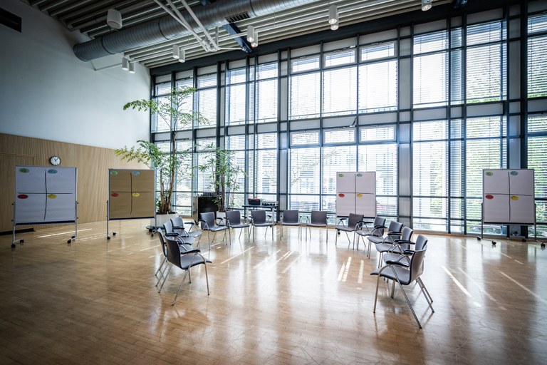 Im Bild ist ein Stuhlkreis in einem großen Konferenzraum dargestellt