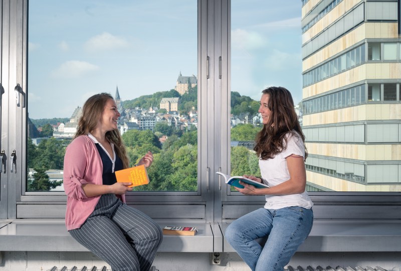 Studierende und Dozentin im Gespräch im Seminarraum, im Hintergrund das Schloß