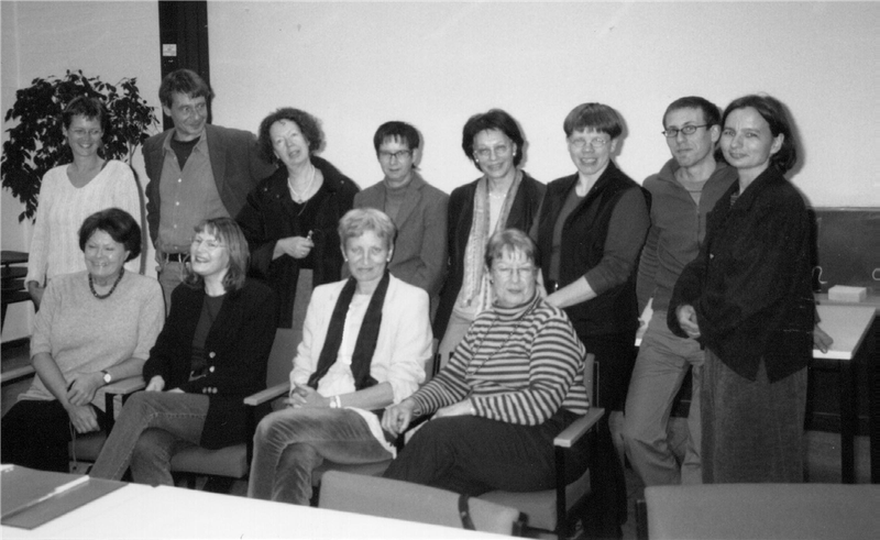 Ein Schwarz-weiß-Foto zeigt 12 Personen, die für ein Gruppenbild zusammenstehen bzw. -sitzen.