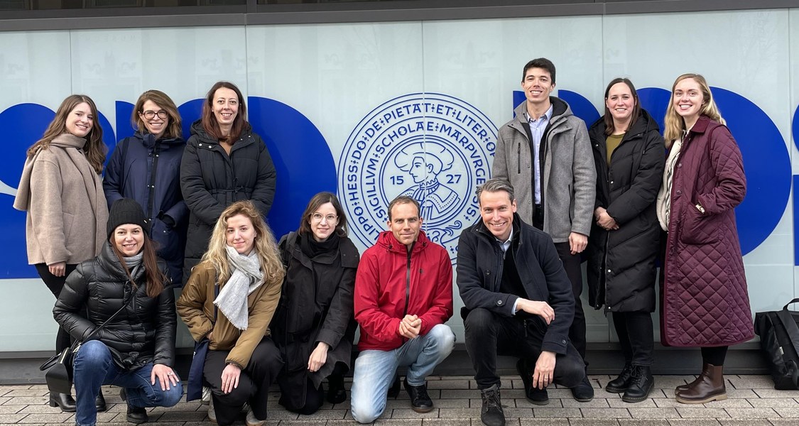 The International Embint Consortium is gathered for a group photo in front of Marburg University's logo.