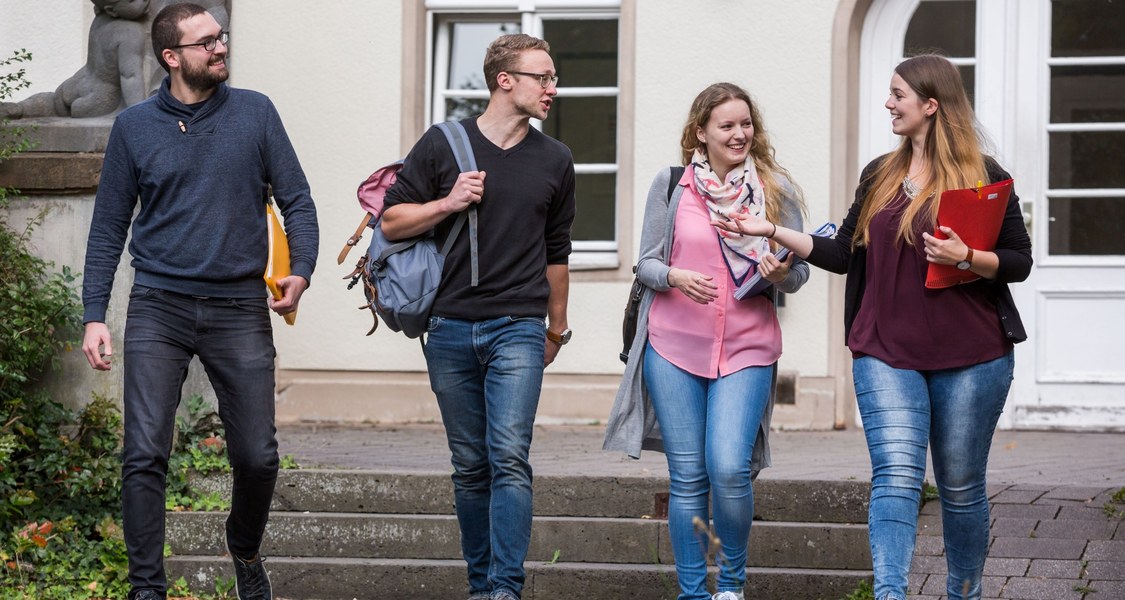 Vier Studierende laufen vom Carolinenhaus weg und unterhalten sich.