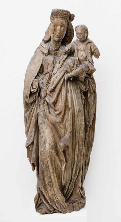 Maria trägt das Jesuskind, welches in einen Mantel gehüllt ist, auf ihrem linken Arm. Sie trägt eine lange Robe und einen Schleier unter ihrer Krone, welche ihr langes Jahr bedeckt.