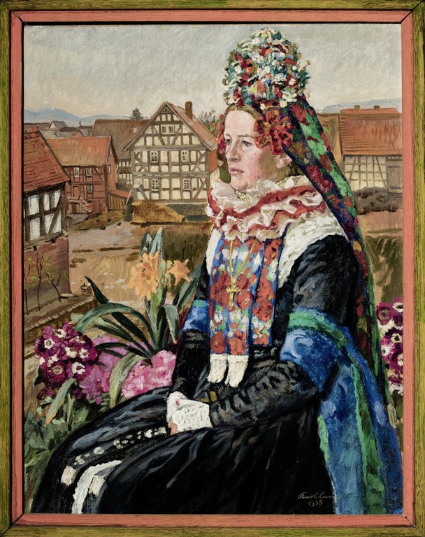 Frau in traditioneller Mardorfer Hochzeitstracht. Hinter der von Blumengewächsen umgebenen Braut zeigt sich eine Dorflandschaft.