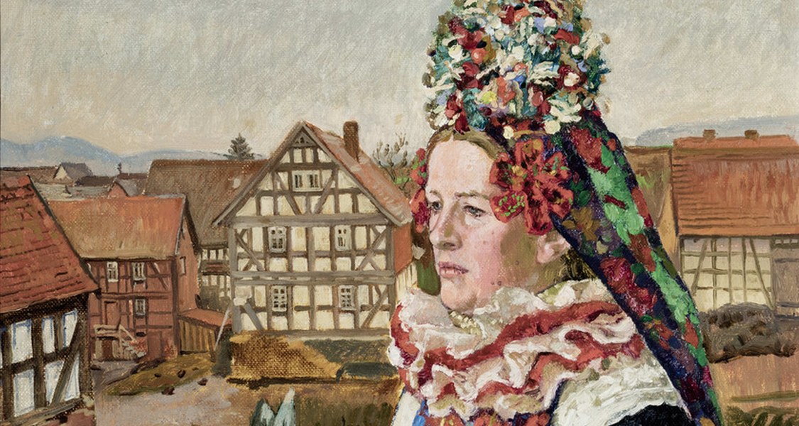 Frau in traditioneller Mardorfer Hochzeitstracht. Hinter der von Blumengewächsen umgebenen Braut zeigt sich eine Dorflandschaft.