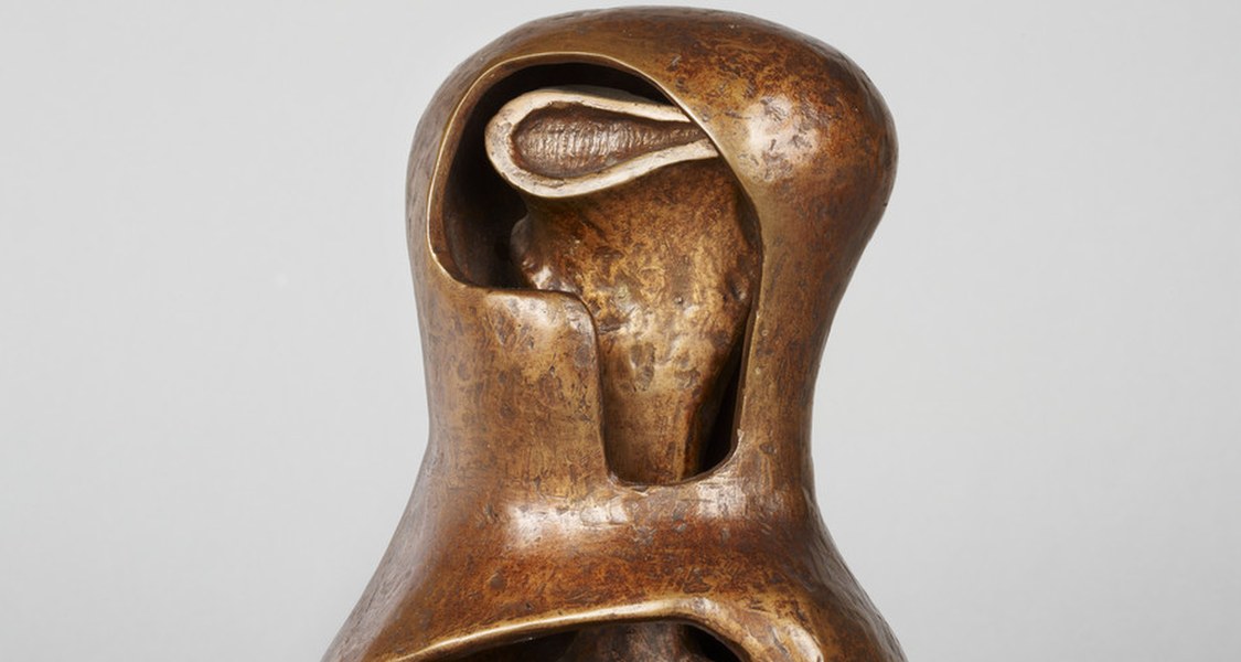 Kleinformatige Bronzeplastik; unter einem fast gänzlich umschlossenen Helm, lugt der Kopf eines Zyklopen hervor.