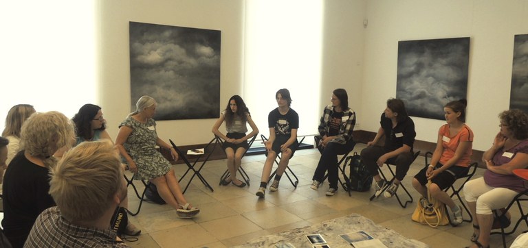 Eine Gruppe sitzt im Stuhlkreis im Foyer des Museums. Die Künstlerin Doris Conrads leitet hier einen Kreativworkshop zum Thema "Wolken inklusiv(e)".