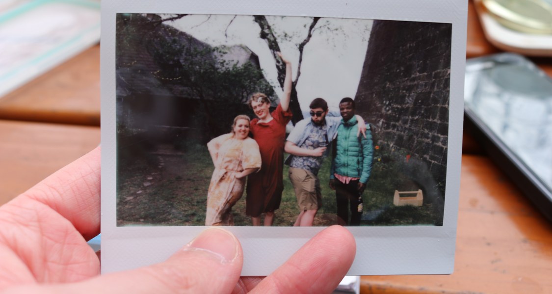 Eine Hand hält ein Polaroid-Gruppenfoto von einer der Stationen während der Hausrallye.