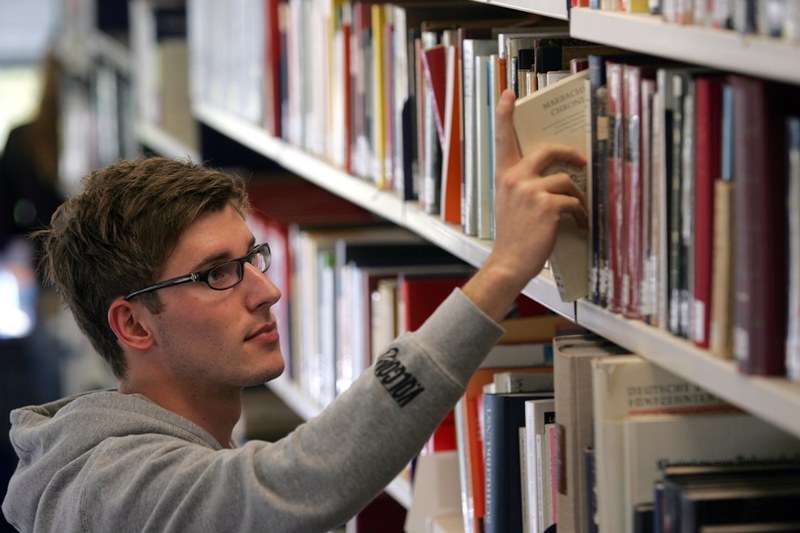 Ein Student stellt ein Buch zurück in ein Bücherregal.