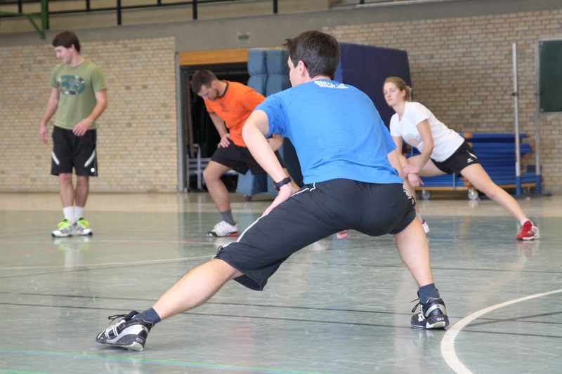 Studierende in Sportkleidung beim Dehnen in der Turnhalle.