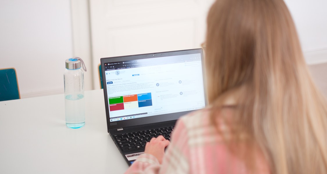 Eine Studentin blickt auf einen Laptop, auf dem die Marvin-Startseite geöffnet ist.