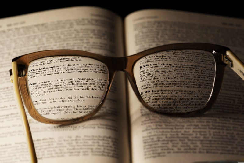 Eine Brille fokussiert Seiten in einem rechtsbezogenen Buch.