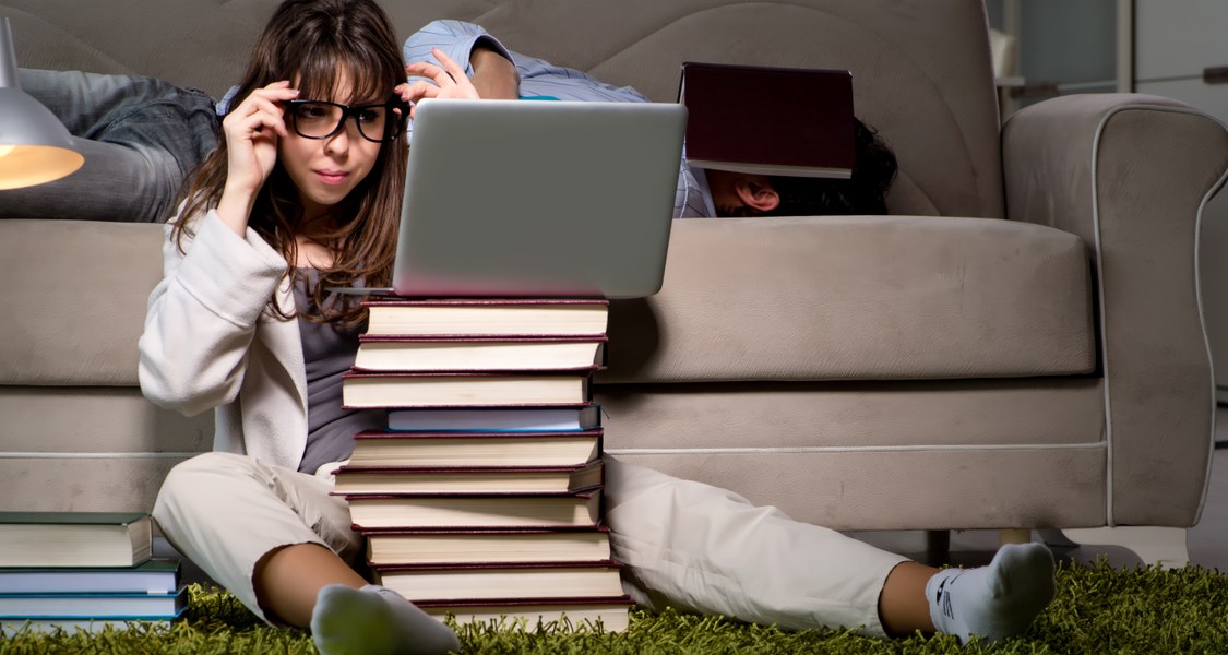 Foto einer Studentin vor einem Bücherberg