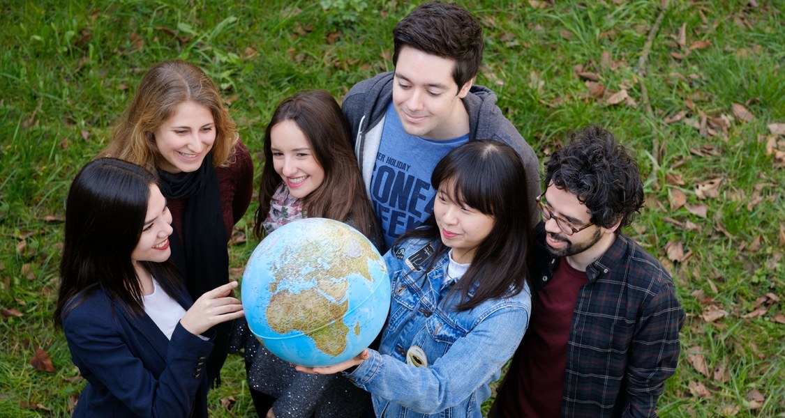 Eine Gruppe Studierende betrachtet einen Globus