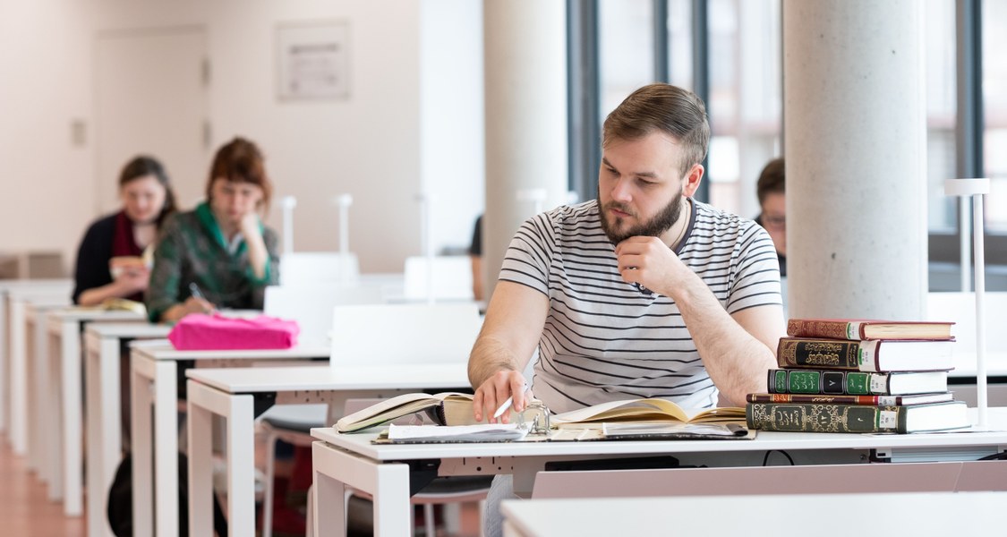 Ein Student lernt an einem der Tische im offenen Lesebereich der neuen Universitätsbibliothek.