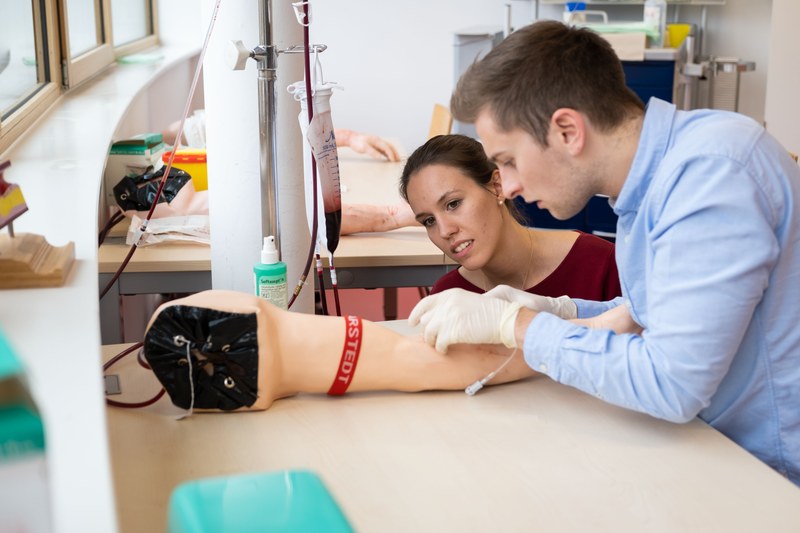 Ein Student übt das Blutabnehmen an einem Modell des menschlichen Arms.