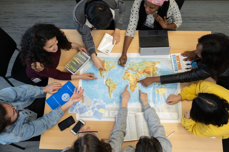 Mehrere Studierende deuten auf verschiedene Länder der Weltkarte.