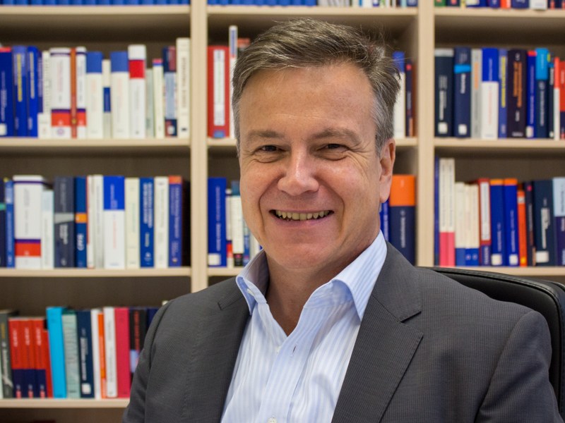 Portrait eines Professors vor einem Bücherregal.