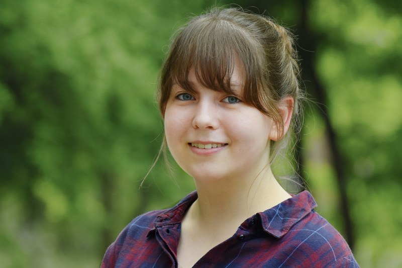 Portrait einer Studentin vor grünem botanischen Hintergrund.