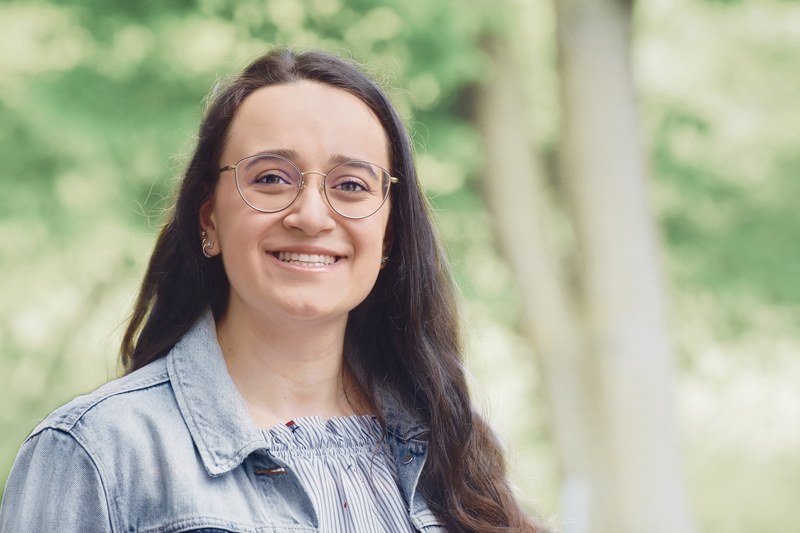 Portrait einer Studentin vor grünem botanischen Hintergrund.