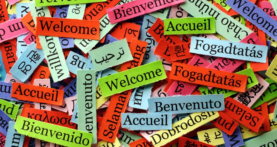 Bunte Farbstreifen mit Willkommensgruß in verschiedenen Sprachen