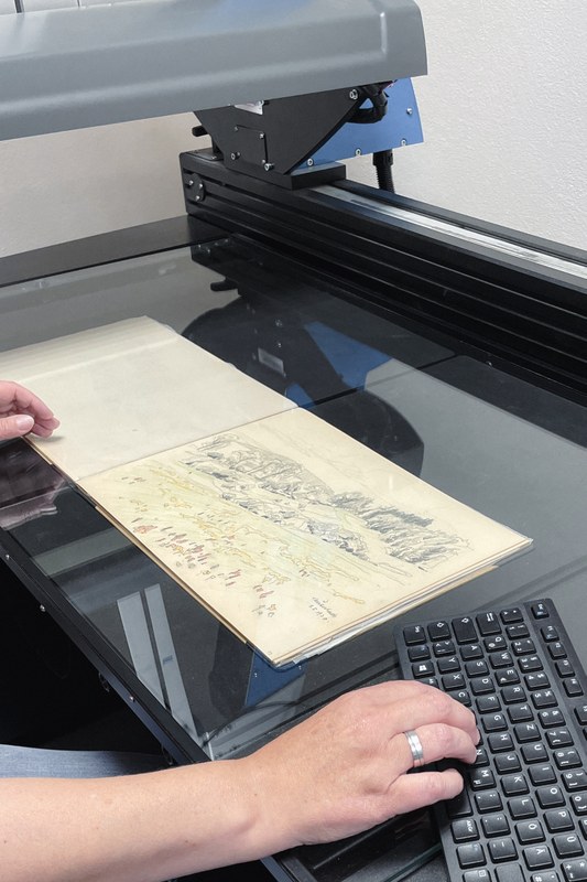 Eine UB Mitarbeiterin scannt ein Ubbelohde Skizzenbuch