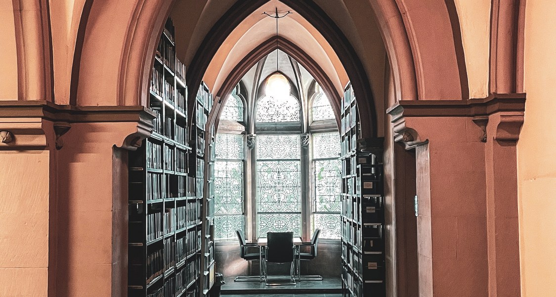 Bücheregale und Sitzgruppe am Fenster in der Bibliothek Evangelische Theologie