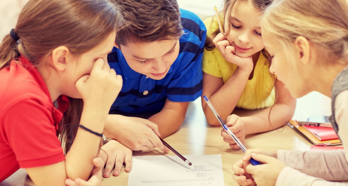 Schulkinder lösen am Tisch Aufgaben.