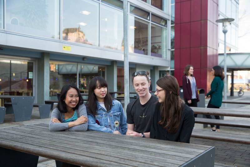 Studierende sitzen am Tisch an der Mensa