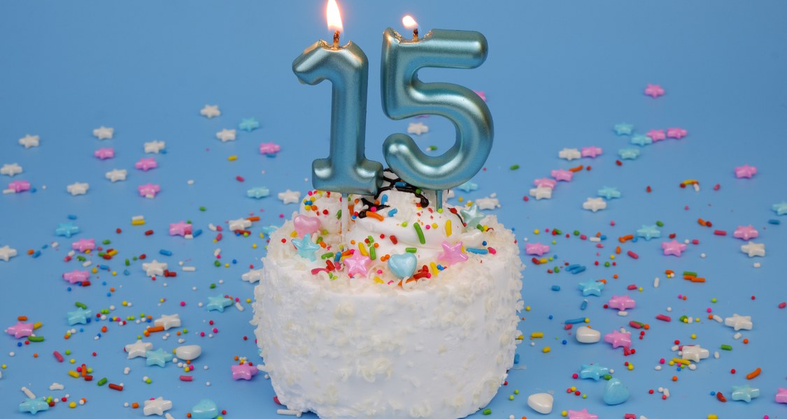 Auf einer Torte brennt eine Kerze mit einer 15.
