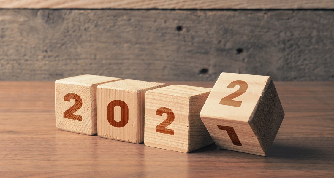 Auf dem Bild sind vier hölzerne Würfel mit den Zahlen 2, 0 und 2 zu sehen. Der letzte Würfel wird von der Zahl 1 auf 2 gedreht, sodass sich die Jahreszahl 2022 ergibt.