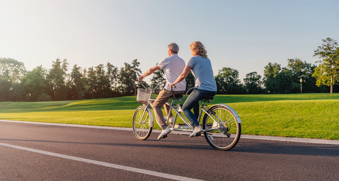 Ein Paar fährt auf einem Tandem durch die Natur.