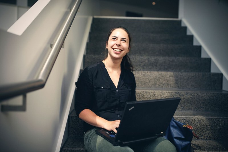 Studentin auf Treppe mit Laptop