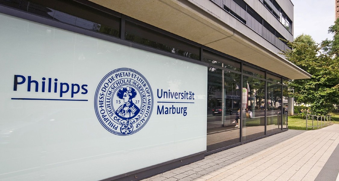 Das Bild zeigt das Logo der Philipps-Universität Marburg am Eingang des Verwaltungsgebäudes in der Biegenstraße 10