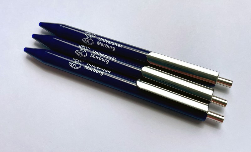 drei blaue Kugelschreiber mit dem Logo der Uni Marburg (stilisierter Philipp und Schriftzug Universität Marburg)