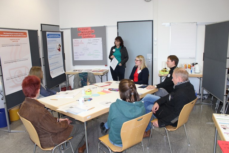 Sieben Menschen bei einem Workshop zusammen an einem Tisch sitzend.