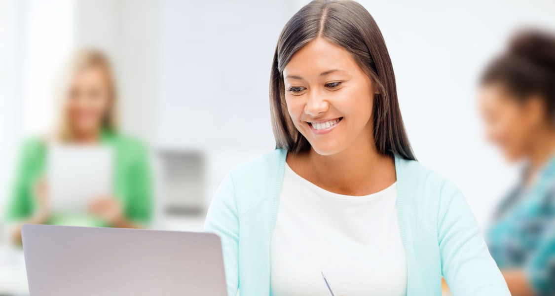 A student smiling in front of a laptop