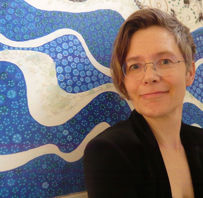 Professorin Anika Oettler vor einem weiß-blauen abstrakten Bild