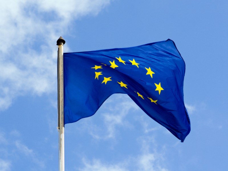 Waving flag of the European Union in front of a blue sky.