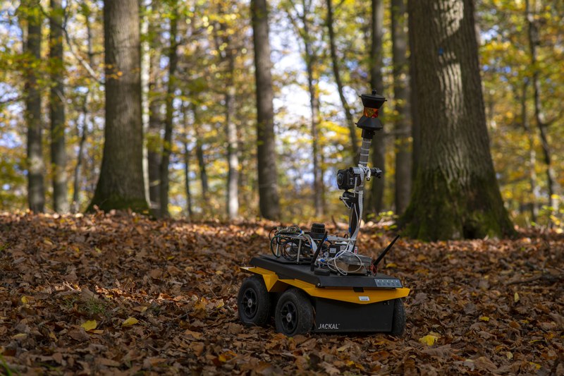 A rover equipped with various sensors driving through the forest.