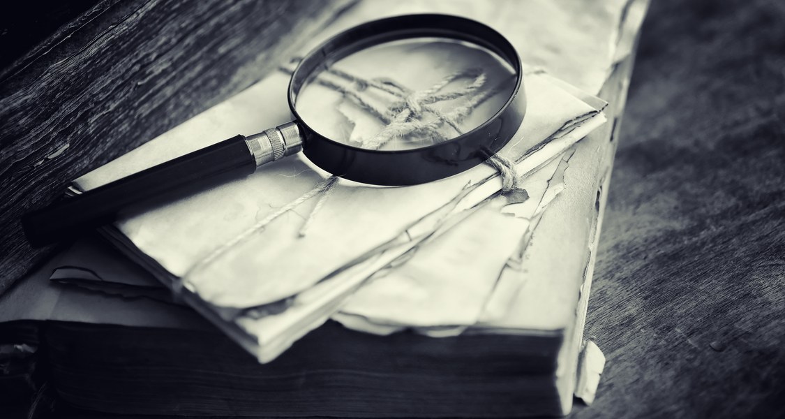 A magnifying glass together with some letters is lying on a table.