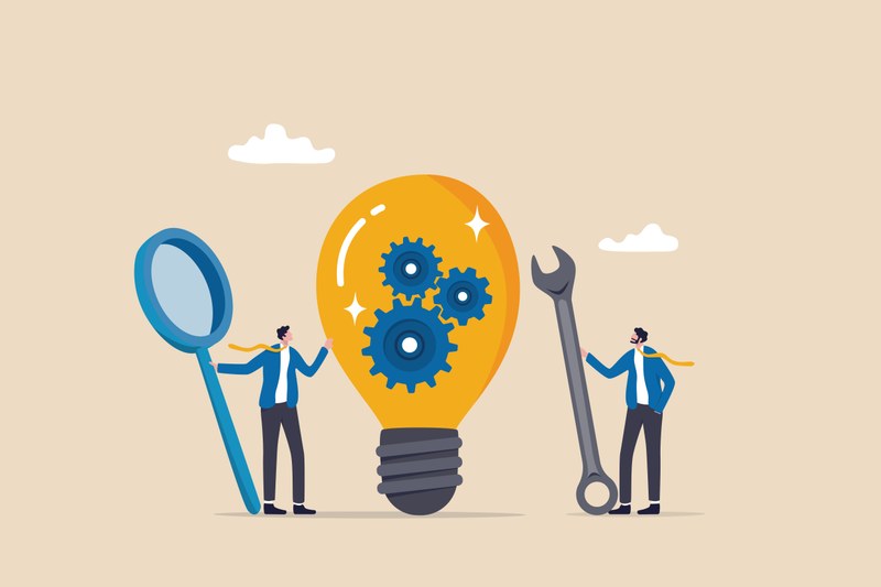 It is a comic-like illustration. In the center is a large illuminated light bulb. Three cogwheels rotate inside each other in the light bulb. To the left of the light bulb is a cartoon character who is stretching out his left arm towards the light bulb. With its right hand, it is holding a magnifying glass that is larger than the figure itself. To the right of the light bulb is another cartoon character. It is facing the light bulb and the other figure. In her right hand, she is holding a tool wrench that is larger than the person herself.