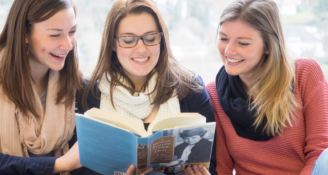 Three women sitting and reading a book