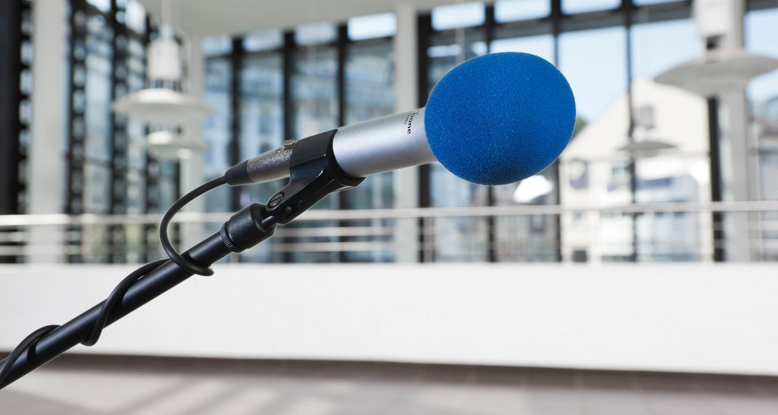Microphone lying on top of a table with a couple of chairs in the background