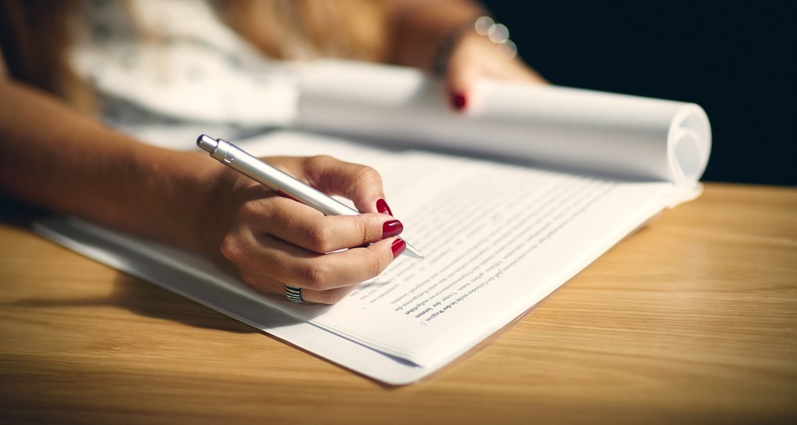 Close-up view of a hand with a pen that is revising a text